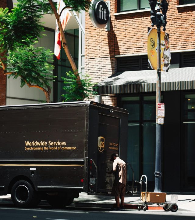UPS delivery courier loading packages into truck on urban street, showcasing transportation and logistics.